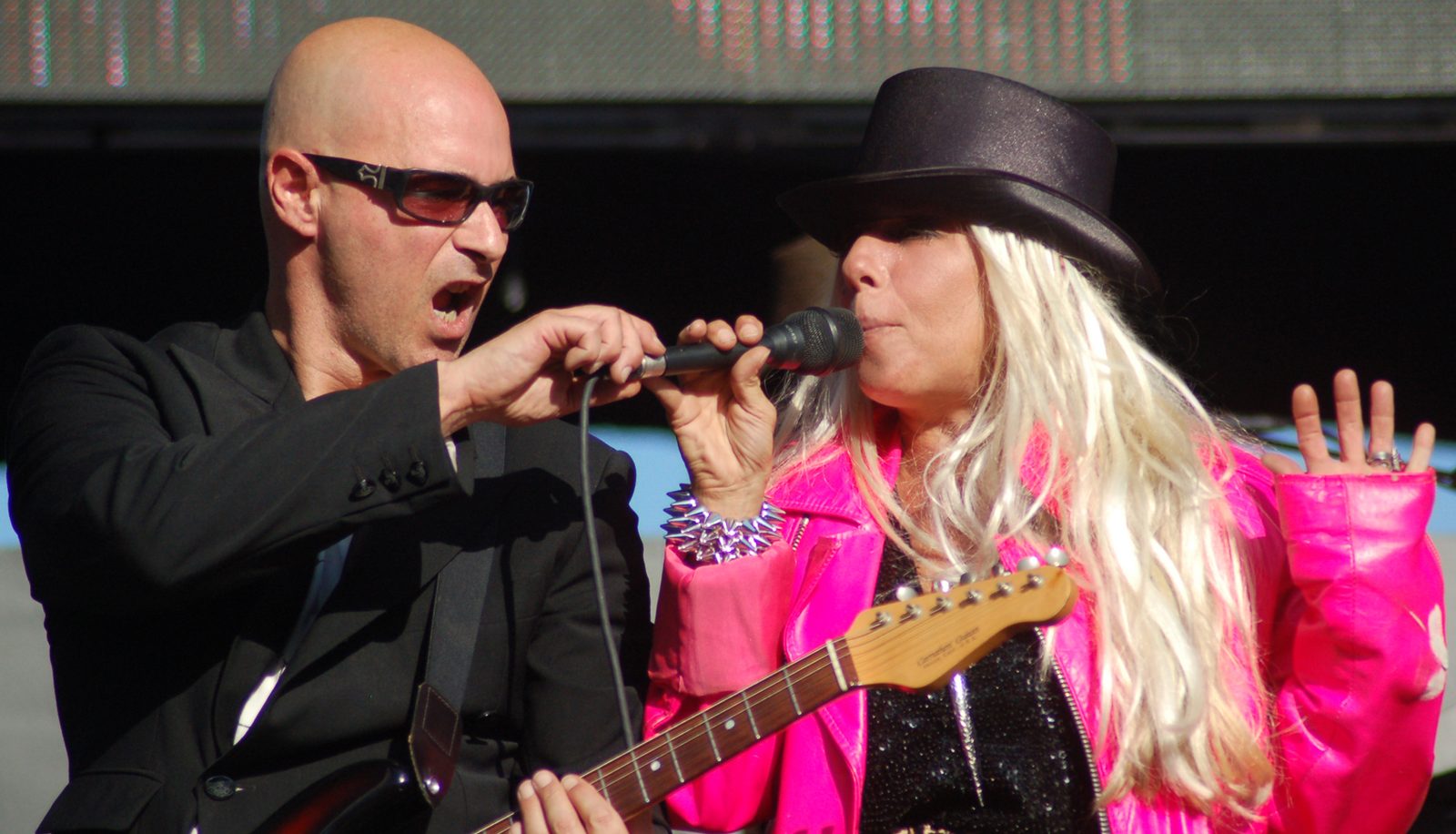 Warren Cuccurullo and Dale Bozzio sharing a microphone during a Missing Persons performance
