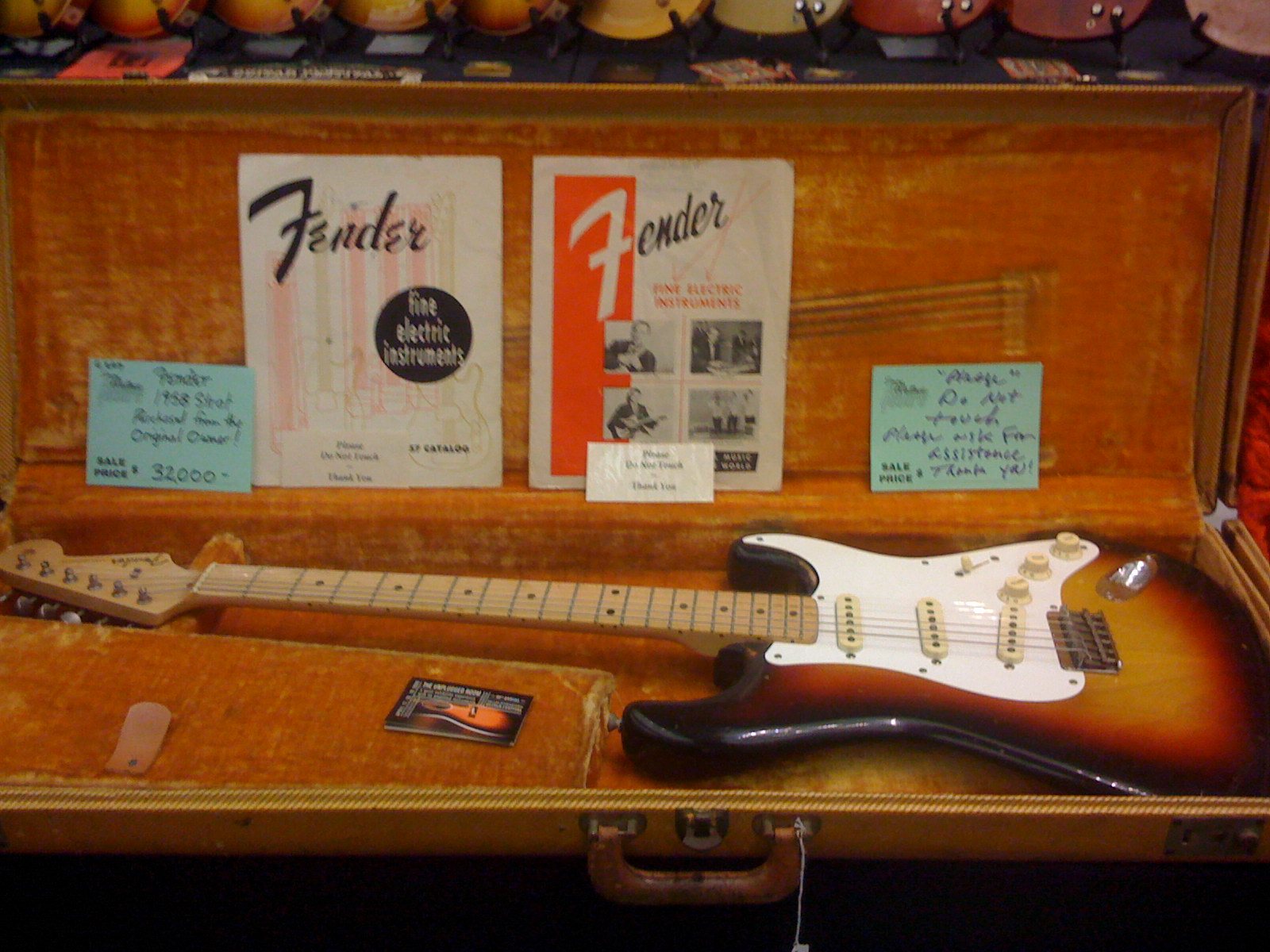 A 1958 Fender Stratocaster in sunburst, lying in its tweed case beside 1957 Fender catalogues