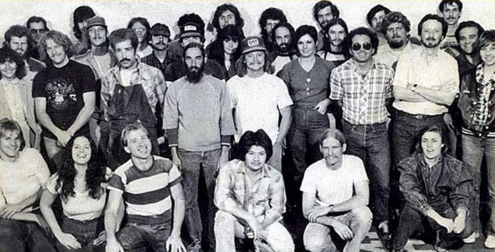Black and white 1970s group photograph of several dozen guitar shop staff
