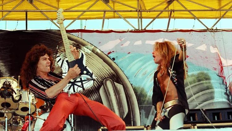 Eddie Van Halen playing the black and white striped Frankenstein on an outdoor stage beside David Lee Roth