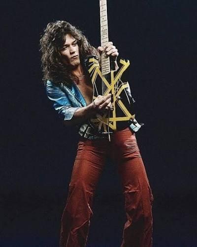 Eddie Van Halen holding the black and yellow striped Bumblebee guitar against a dark background